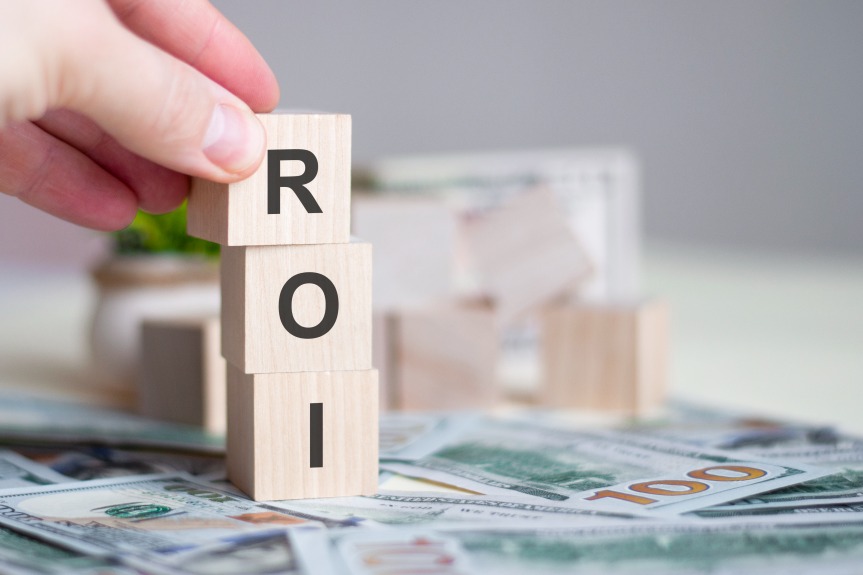ROI Return on Investment 100 Dollars Bills Wooden Blocks Hand