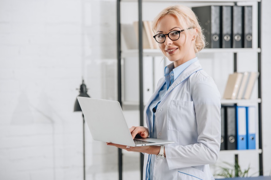 Chiropractor Doctor Woman Female Laptop Smiling Side View Practice