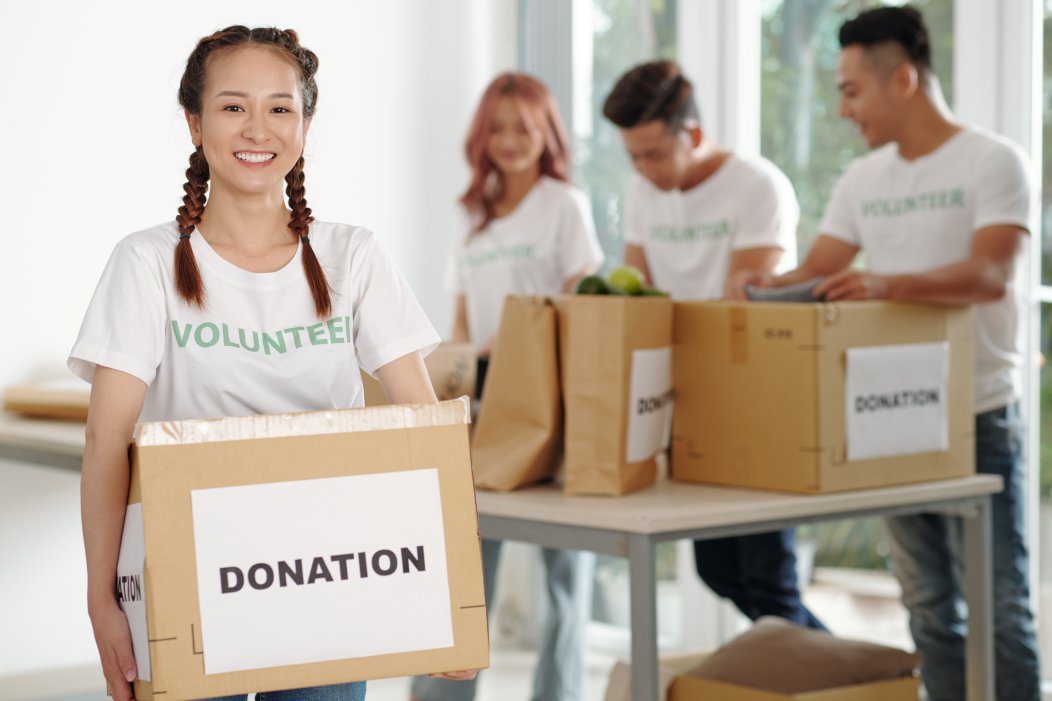 Box packed for charity center carried by a smiling woman