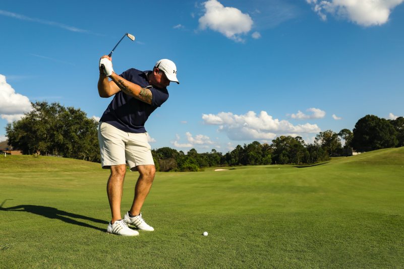 Man Swinging a Golf Club on a Green Golf Course