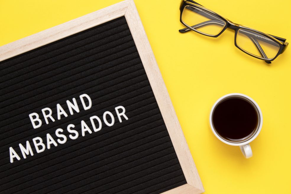 Brand Ambassador Text on letter board and coffee cup on yellow background