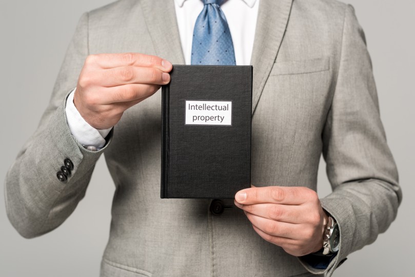 Protect Intellectual Property IP Book Businessman Holding Suit Tie