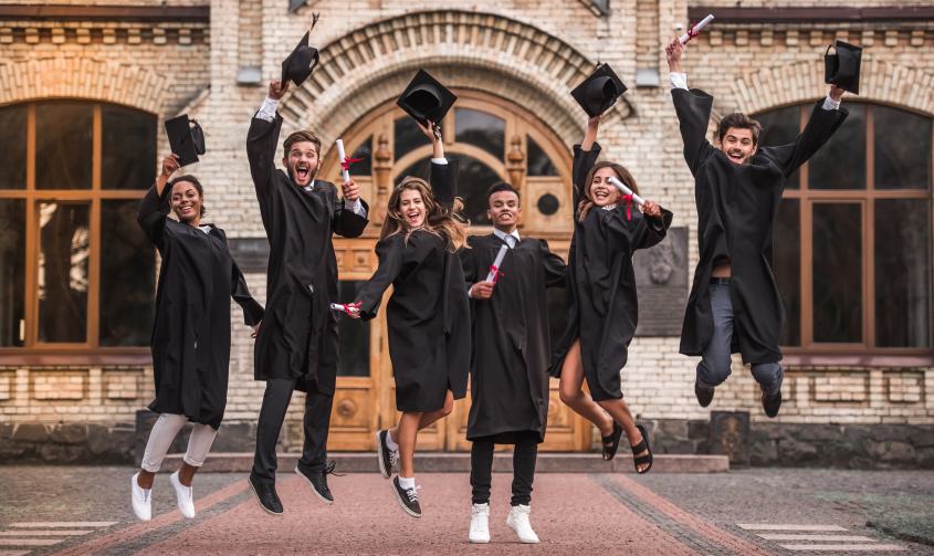 Happy Young College Alumni Students Jumping Graduating