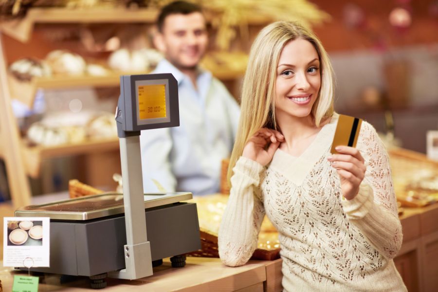 Woman at the cashier satisfied with her purchase while holding credit card