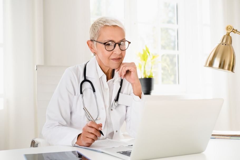 Mature Female Doctor White Scrub Telemedicine Laptop Online Consultation