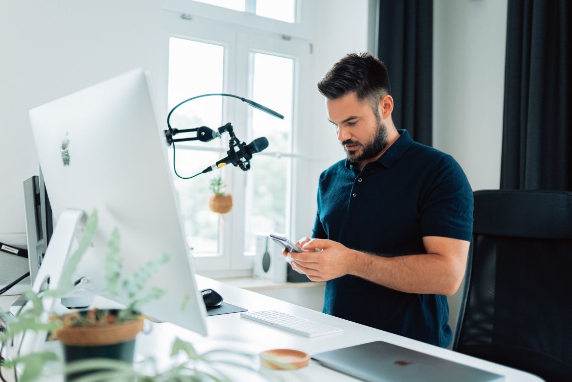 X influencer in front of computer holding phone