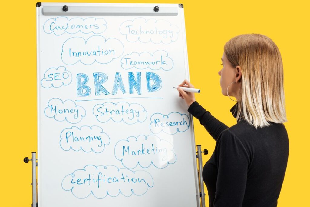 Businesswoman standing near white flipchart with the word ‘brand’