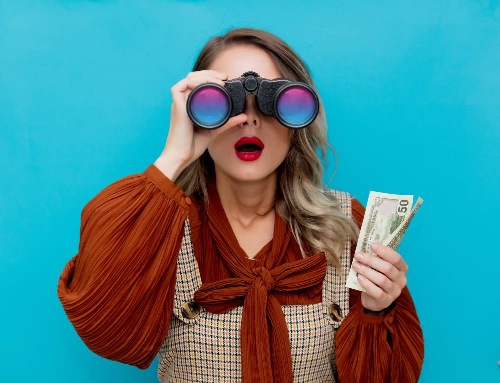 Young woman with cash and binocular on hand