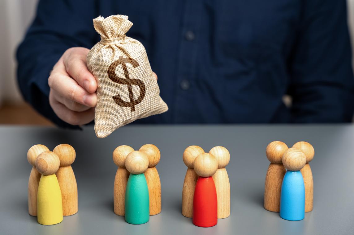 A bag of money and group of wooden figures depicting different market segments
