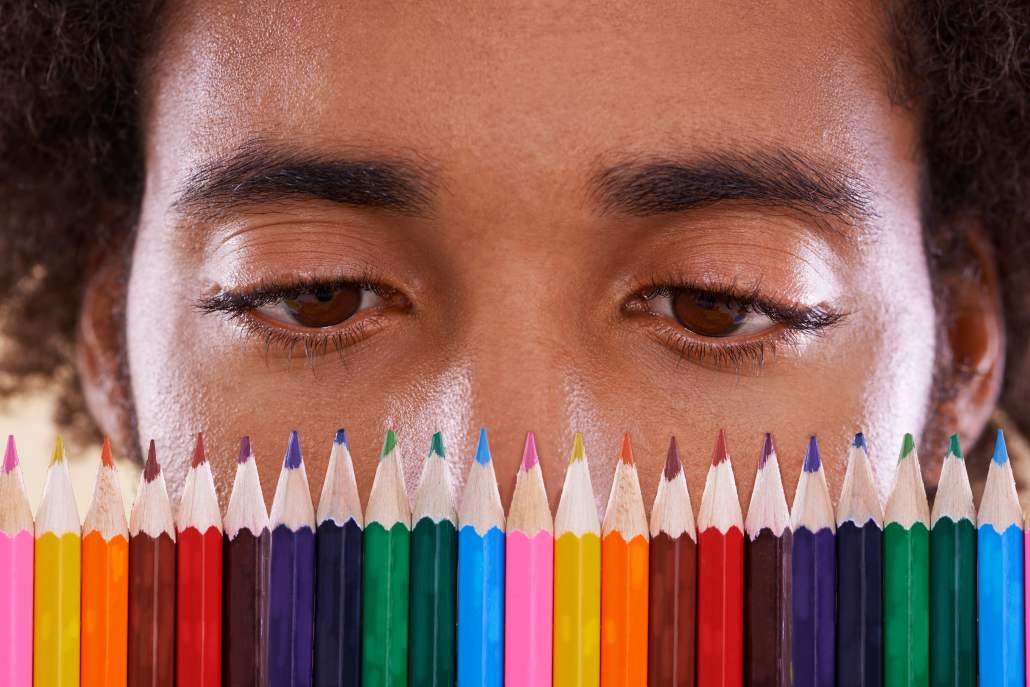 View of a man looking closely at a row of colorful pencil crayons and contrasting them to improve his perception of things