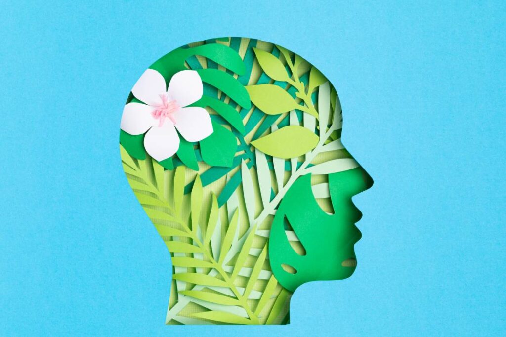 Papercut head with with green leaves inside. Mental health should be considered in discussing negative feedback examples and how to address them.