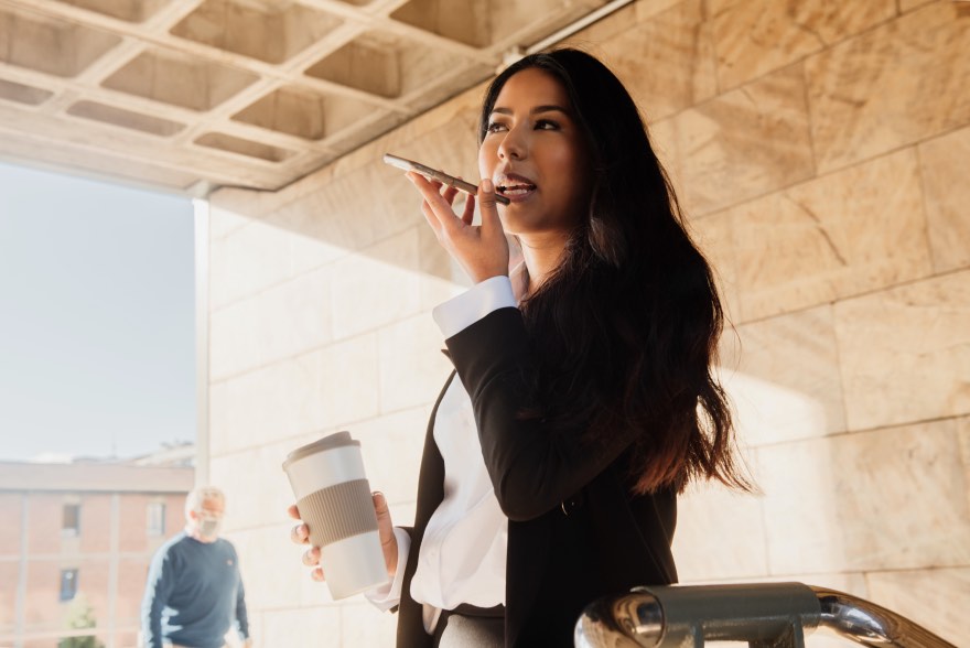 Businesswoman Using Voice Search Smarphone Holding Coffee