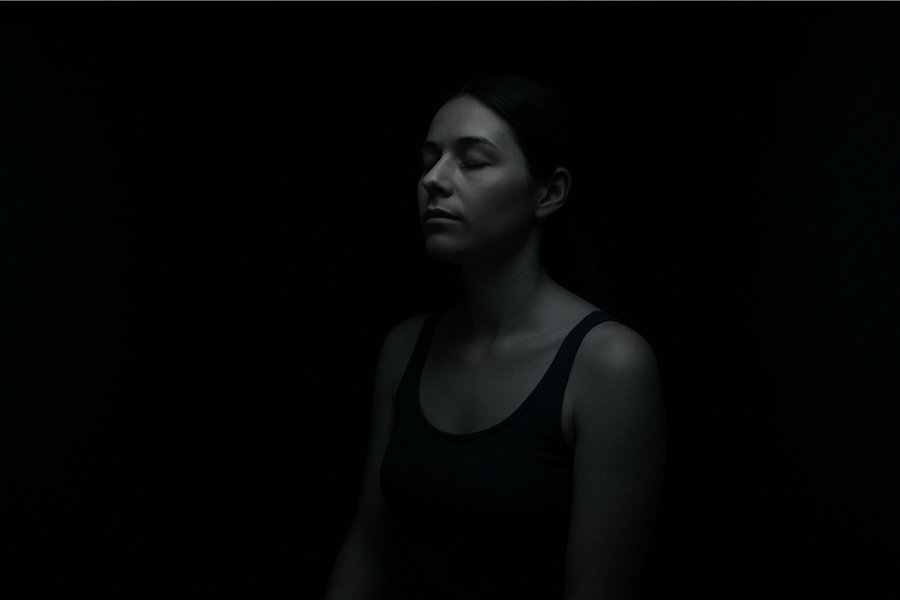 Woman in darkness retreat practicing sensory deprivation for deep relaxation